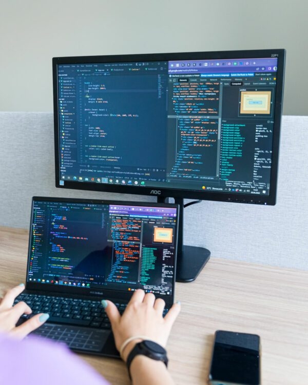 Photos of a laptop connected to a monitor with a coding program open on the screens.